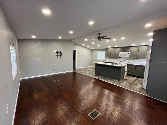 an open kitchen with kitchen island a sink dishwasher stove with wooden floor