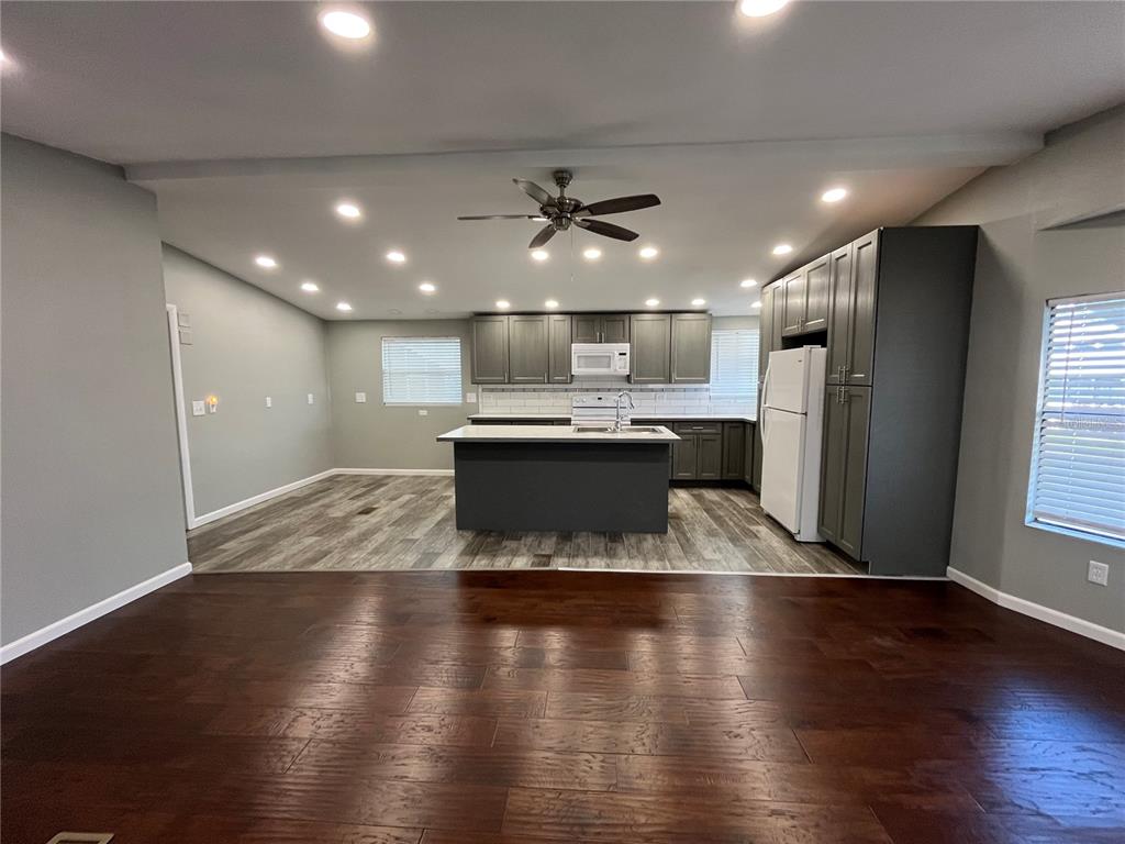 12100 Seminole Boulevard, Unit 365 Largo, FL 33778 - Photo 10 of 32 an empty room with wooden floor and a kitchen space