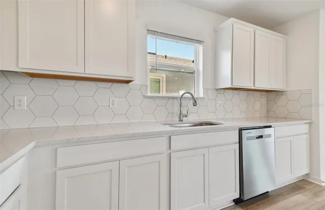 a kitchen with white cabinets and sink
