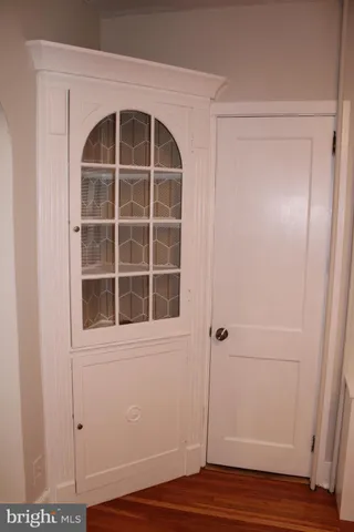 an empty room with wooden floor mirror and windows
