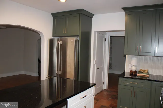 a kitchen with granite countertop a refrigerator and a stove top oven