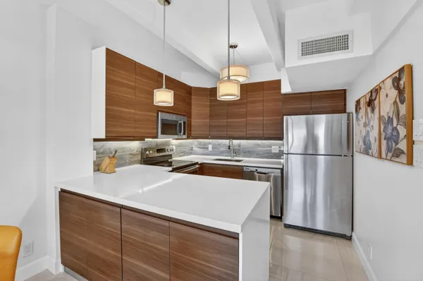 a kitchen with stainless steel appliances a refrigerator a sink a stove and white cabinets