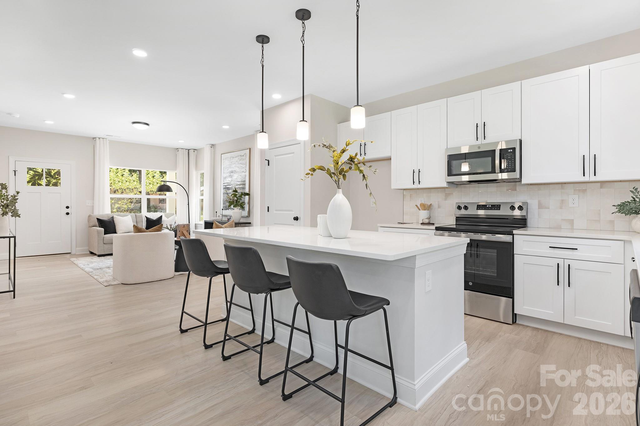 4015 Oakdale Road Charlotte, NC 28216 - Photo 2 of 30 a kitchen with stainless steel appliances kitchen island granite countertop a table chairs in it and white cabinets