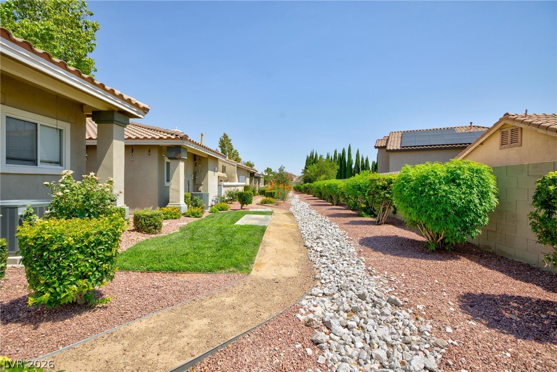3238 Mystic Ridge Court Las Vegas, NV 89129 - Photo 23 of 31 A well-maintained community path winds through desert landscaping, bordered by neatly trimmed shrubs and tiled-roof homes.