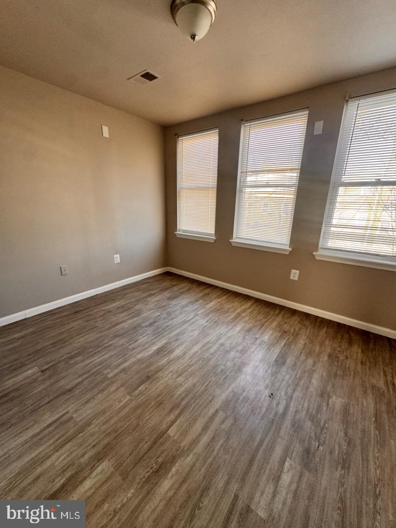 1020 Bennett Place Baltimore, MD 21223 - Photo 4 of 8 an empty room with wooden floor and windows