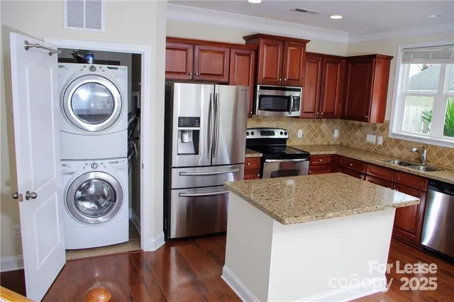 a kitchen with stainless steel appliances granite countertop a refrigerator a stove top oven a sink and dishwasher