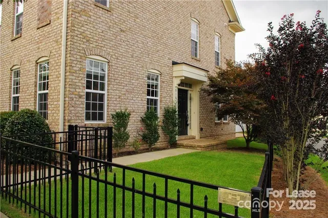a view of a house with a small yard and wooden fence