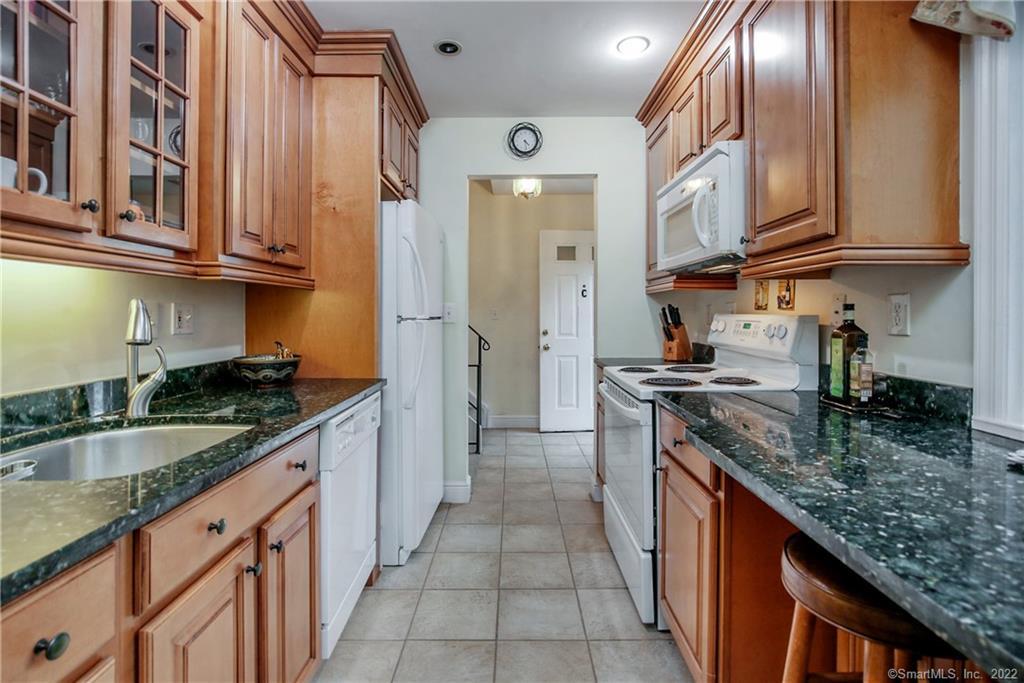 a kitchen with granite countertop stainless steel appliances a sink dishwasher refrigerator stove and cabinets
