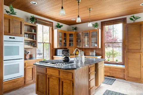 a kitchen with kitchen island granite countertop a large window and stainless steel appliances