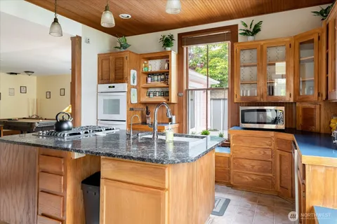a kitchen with stainless steel appliances granite countertop a stove a sink and a microwave oven with granite countertops