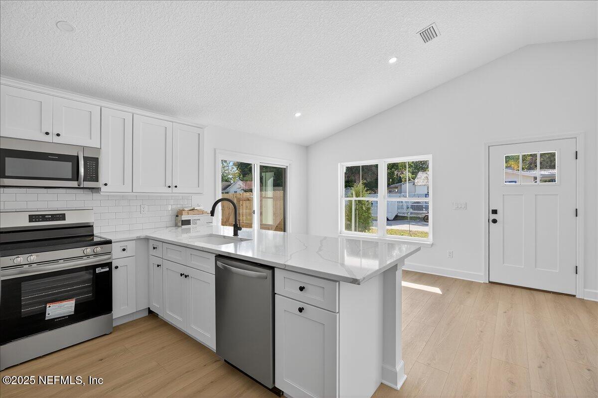 69 Josiah Street St. Augustine, FL 32084 - Photo 11 of 50 a kitchen with granite countertop a stove a sink a window and wooden floors