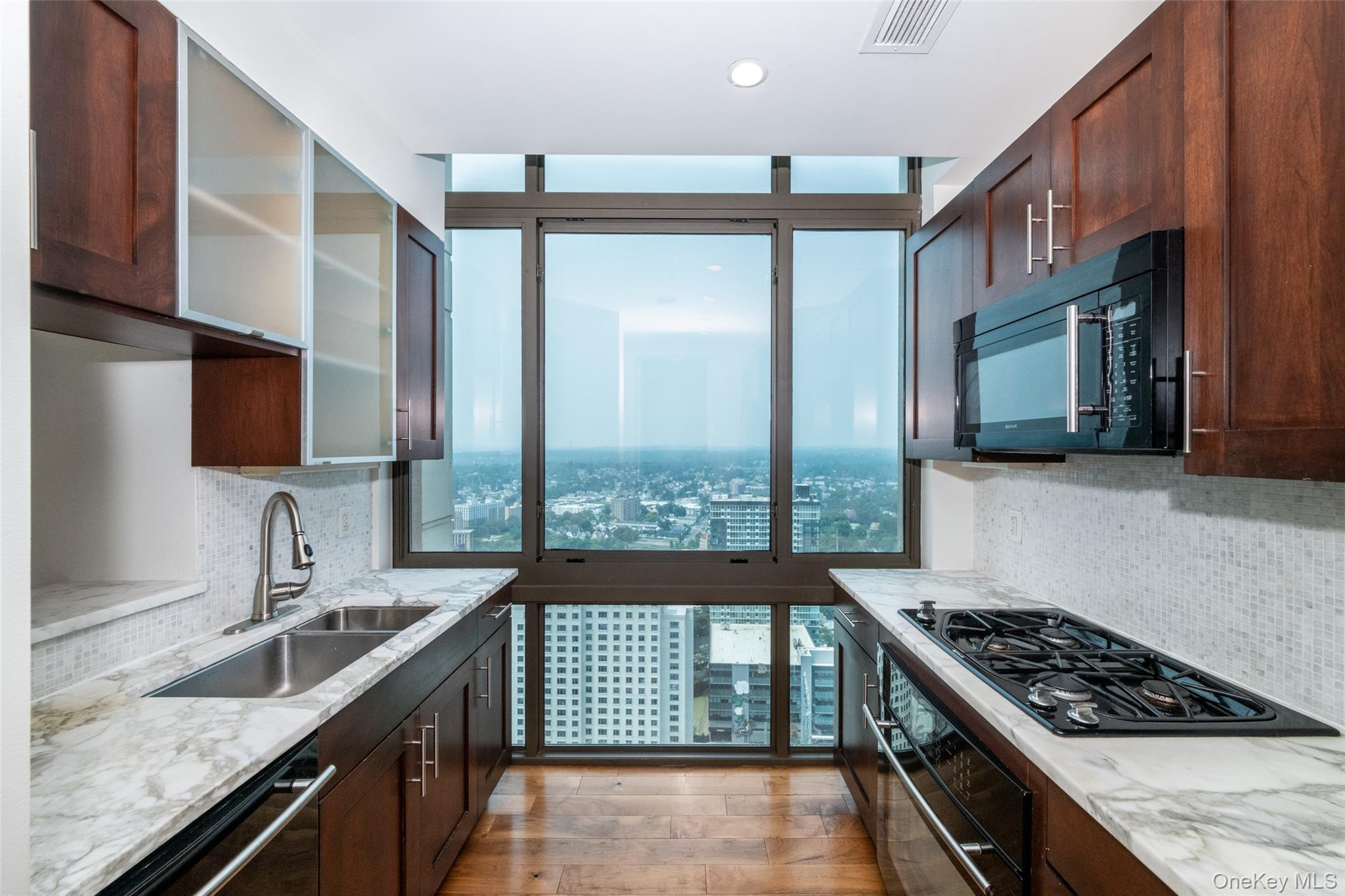 175 Huguenot Street, Unit PH204 New Rochelle, NY 10801 - Photo 2 of 10 Kitchen featuring backsplash, light stone countertops, black appliances, light wood finished floors, and recessed lighting