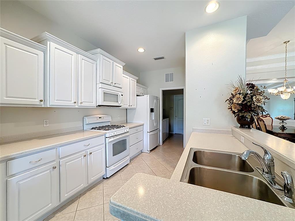 8721 Stone Harbour Loop Bradenton, FL 34212 - Photo 17 of 71 a kitchen with white cabinets a sink stove and refrigerator