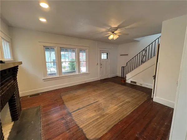a view of an empty room with wooden floor and a fireplace