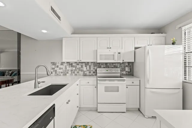a kitchen with white cabinets sink and white appliances
