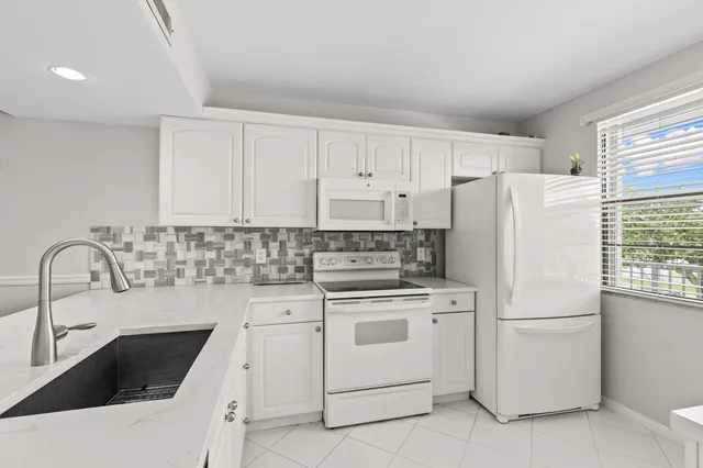 a kitchen with white cabinets sink and white appliances