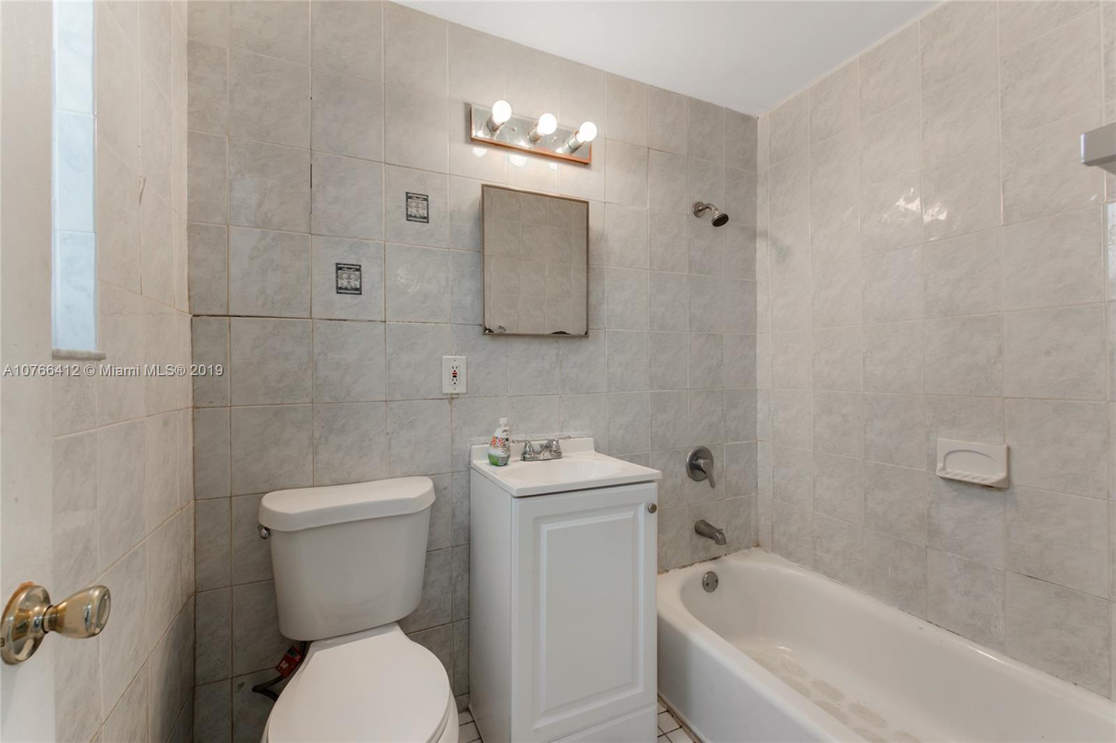 330 74th Street, Unit 7 Miami Beach, FL 33141 - Photo 11 of 27 a white toilet sitting next to a bathtub