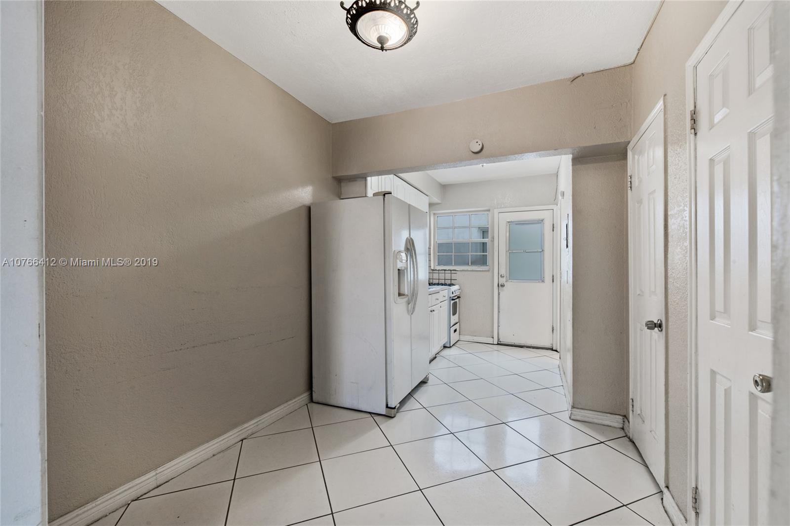 330 74th Street, Unit 7 Miami Beach, FL 33141 - Photo 5 of 27 a view of a refrigerator in kitchen and white cabinets