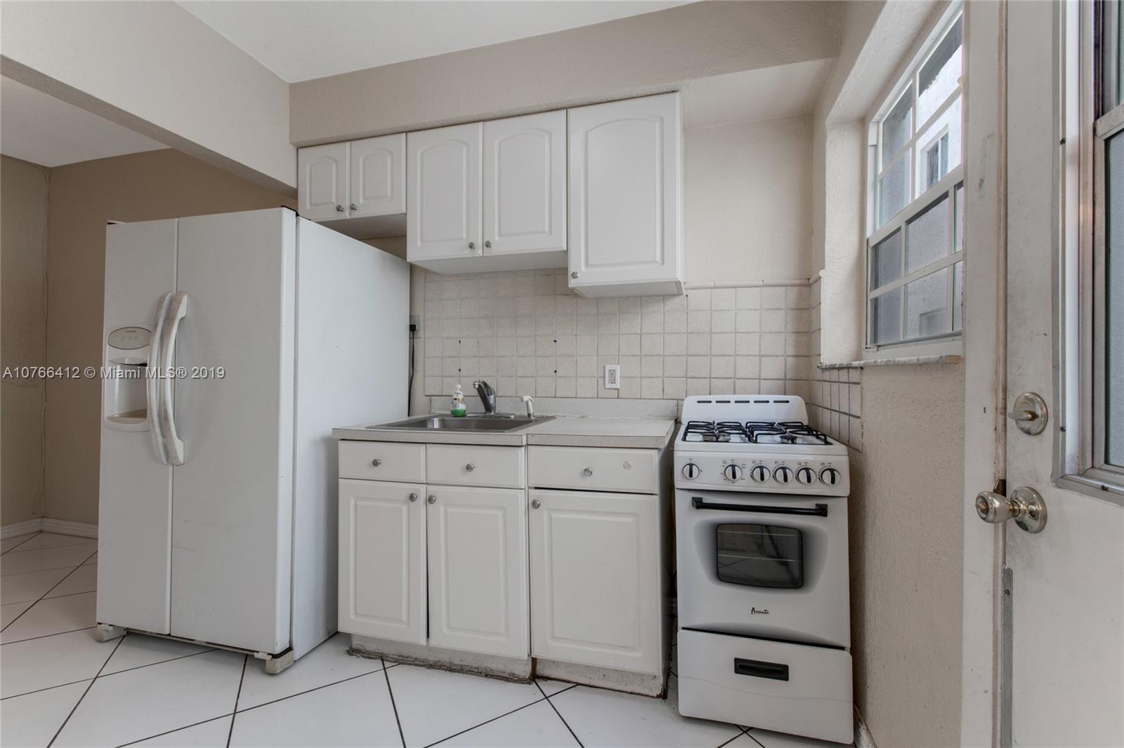 330 74th Street, Unit 7 Miami Beach, FL 33141 - Photo 9 of 27 a kitchen with white cabinets and white appliances