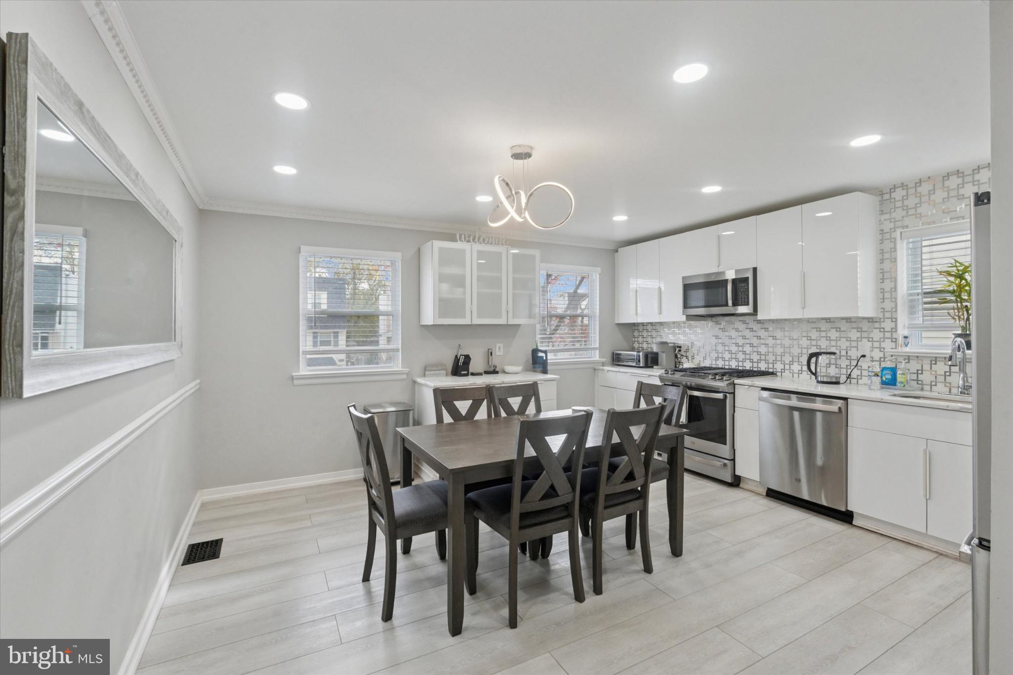 9938 Alicia Street Philadelphia, PA 19115 - Photo 4 of 15 a large white kitchen with granite countertop a stove a sink a dining table and chairs