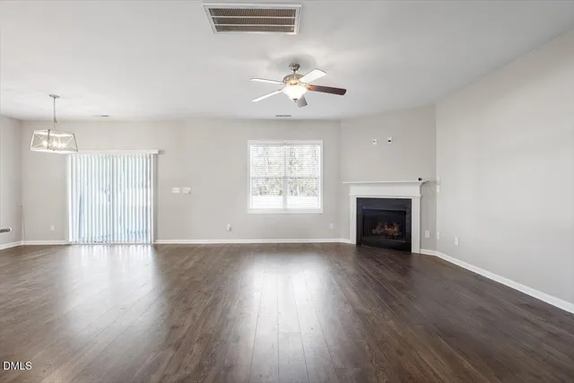 an empty room with wooden floor fireplace and windows