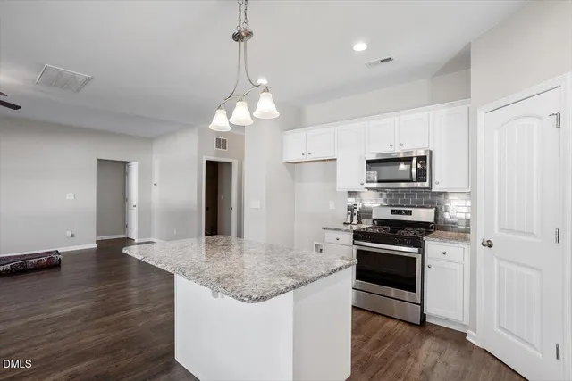 a kitchen with stainless steel appliances granite countertop a stove refrigerator and microwave