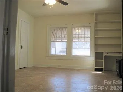 an empty room with a fireplace and windows