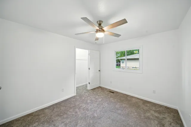 an empty room with a window and a fan