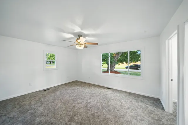 an empty room with windows and chandelier fan
