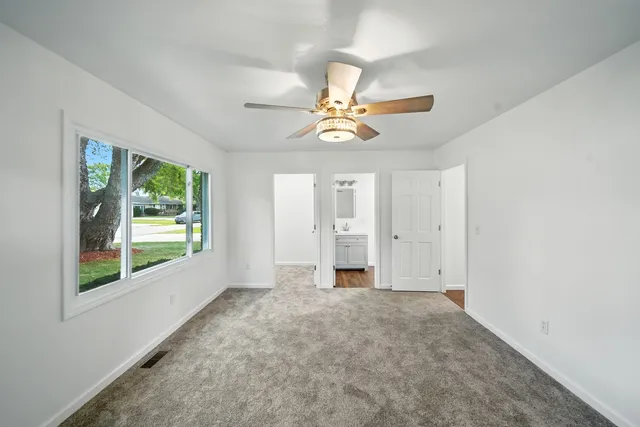 an empty room with windows and fan