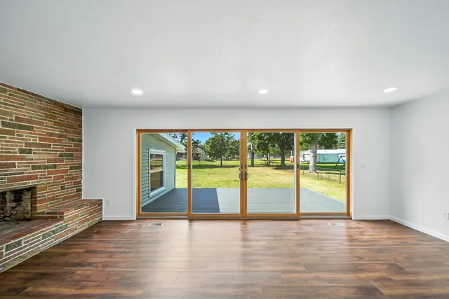an empty room with wooden floor and a fireplace