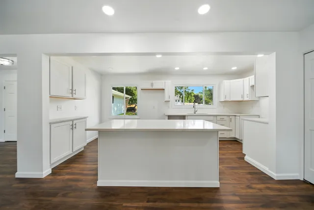 a large white kitchen with lots of counter space wooden floor and appliances