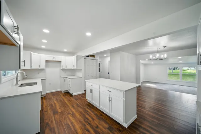 a large white kitchen with kitchen island a sink stainless steel appliances and cabinets