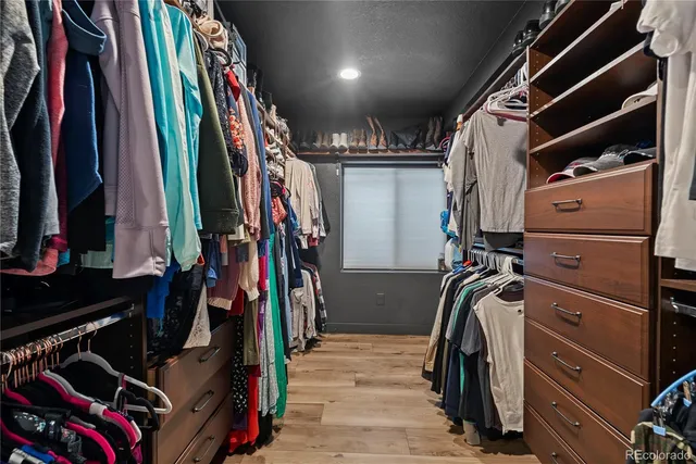 a view of walk in closet with clothes and shoes