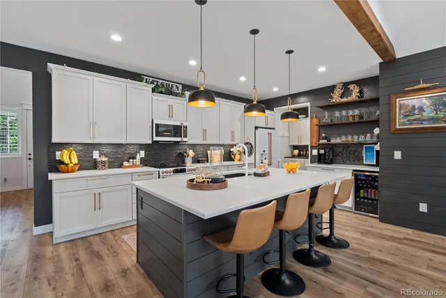 a kitchen with a dining table chairs refrigerator and microwave