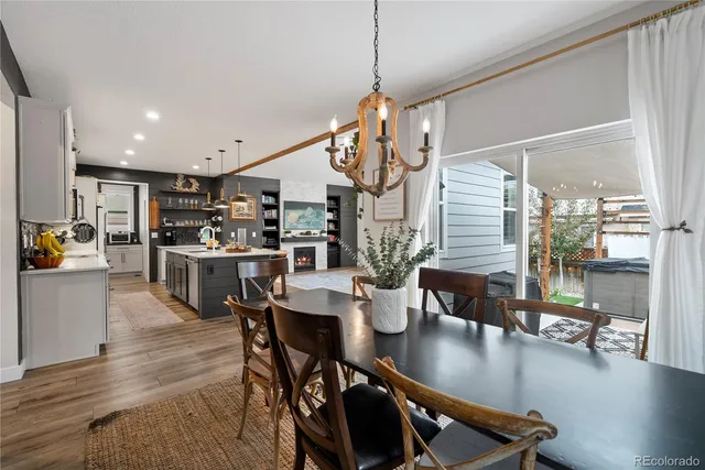 a open dining room with stainless steel appliances kitchen island granite countertop a table chairs and a living room view