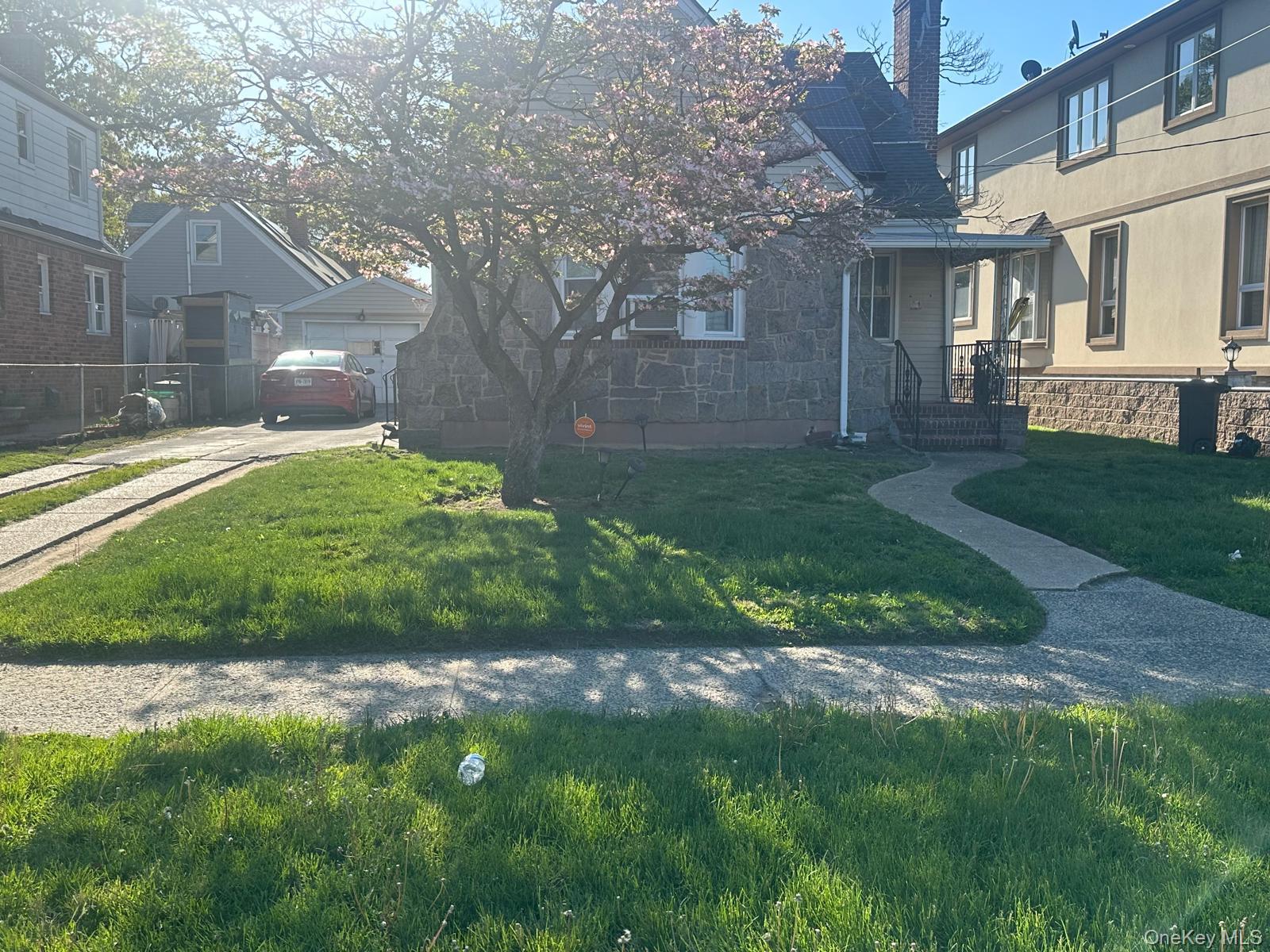 91 Broadway Valley Stream, NY 11580 - Photo 1 of 12 a view of a yard in front of a brick house with plants