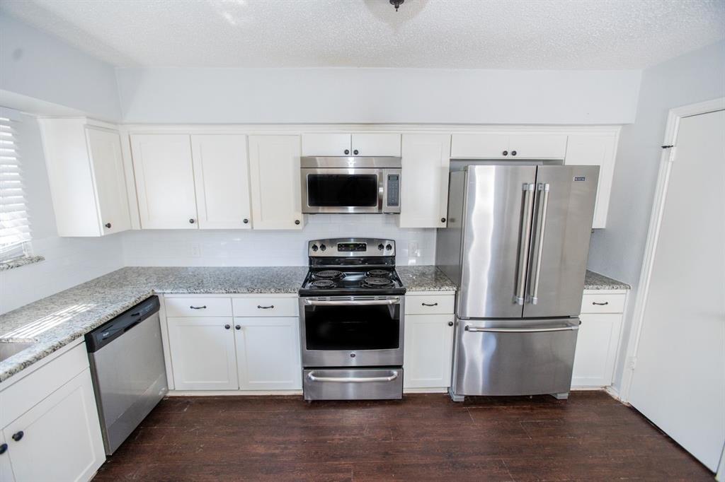 2236 Irwin Street Fort Worth, TX 76110 - Photo 2 of 11 a kitchen with a refrigerator stove and white cabinets