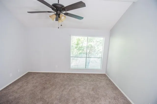 an empty room with a window and a fan