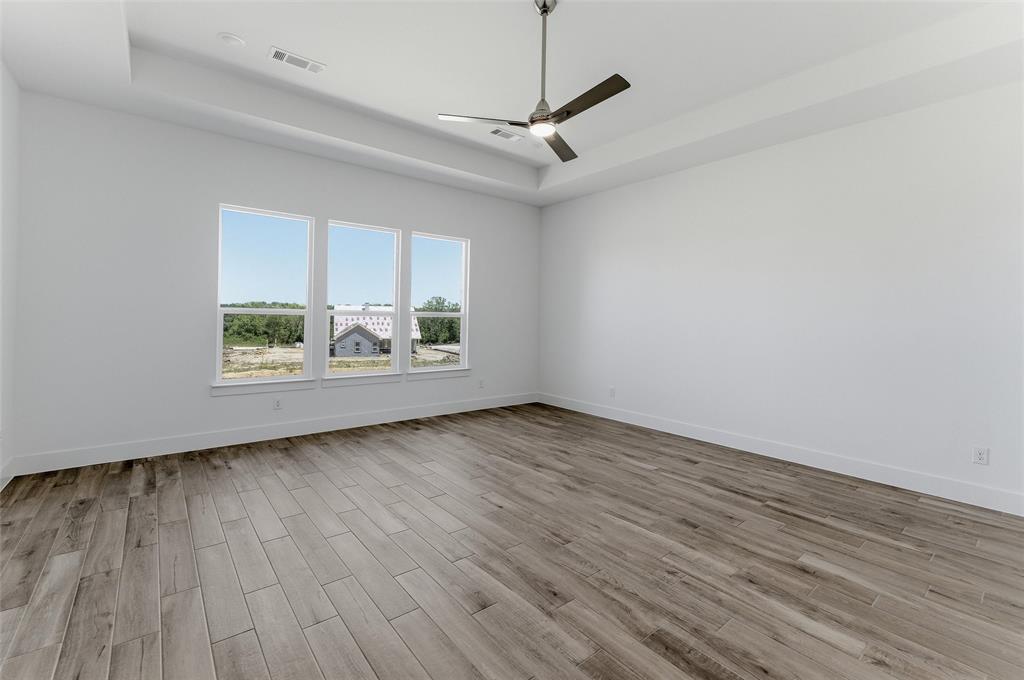 815 Vly Rdg Road Van Alstyne, TX 75495 - Photo 19 of 29 Spacious interior room featuring three large windows, wood-finish flooring, a contemporary ceiling fan, and a tray ceiling