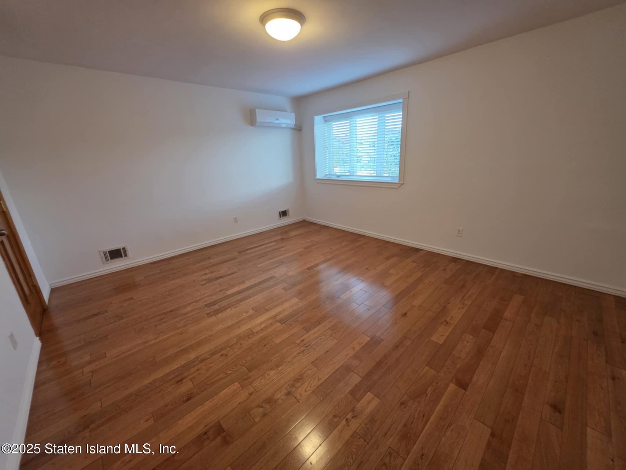58 Selvin Loop Staten Island, NY 10303 - Photo 12 of 19 an empty room with wooden floor and windows