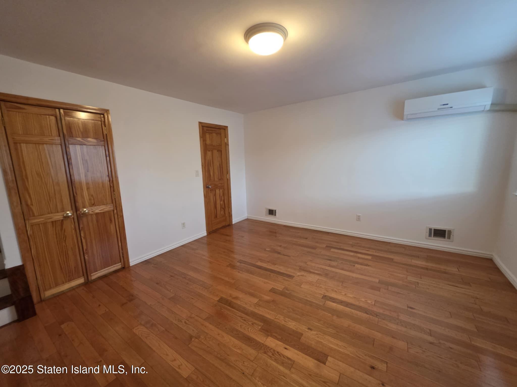 58 Selvin Loop Staten Island, NY 10303 - Photo 13 of 19 an empty room with wooden floor and windows