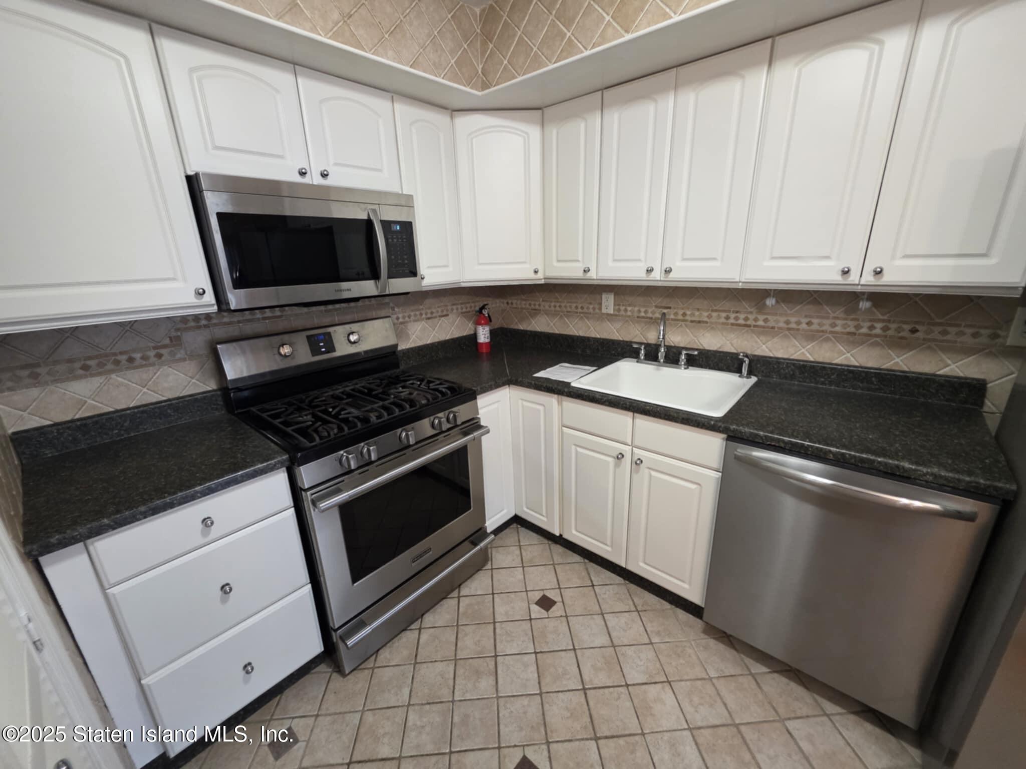 58 Selvin Loop Staten Island, NY 10303 - Photo 8 of 19 a kitchen with white cabinets and appliances