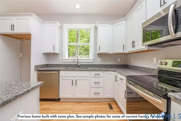 a kitchen with stainless steel appliances granite countertop a stove a sink and a white cabinets