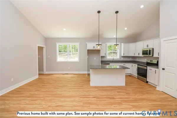 a view of a kitchen with kitchen island a sink stainless steel appliances and window