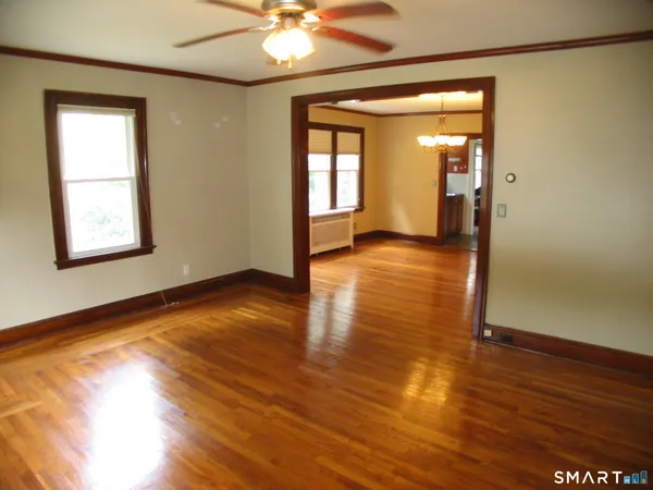 a view of an empty room with wooden floor and a window