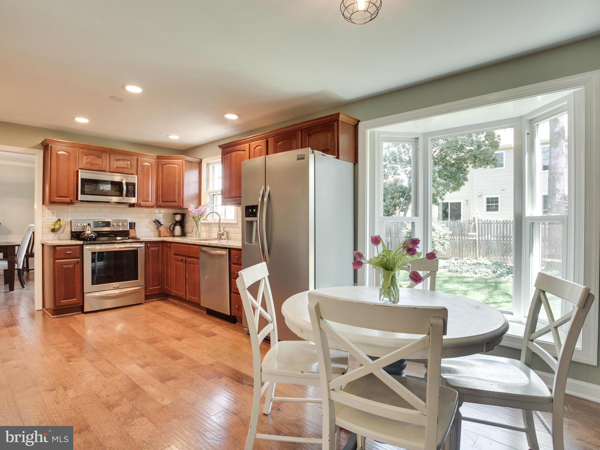 8231 Crown Court Road Alexandria, VA 22308 - Photo 5 of 30 a kitchen with stainless steel appliances kitchen island granite countertop a refrigerator a stove top oven a sink with a dining table and chairs