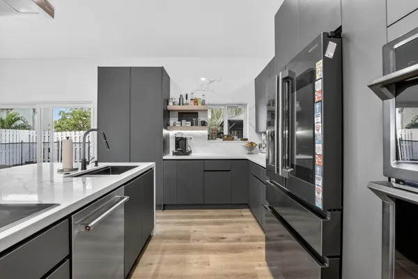 a kitchen with stainless steel appliances granite countertop a refrigerator a sink and white cabinets