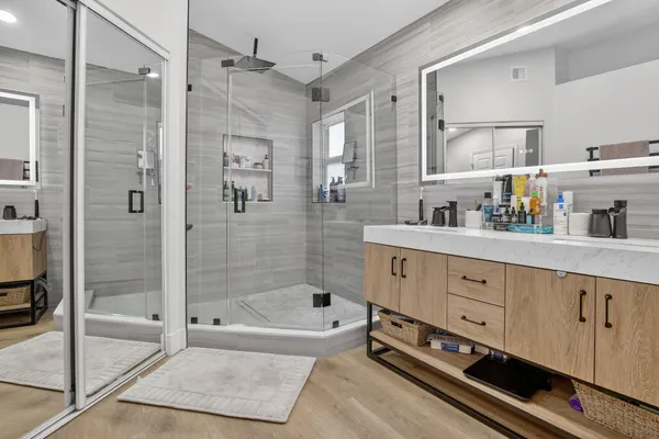 a bathroom with a tub a double vanity sink and glass door