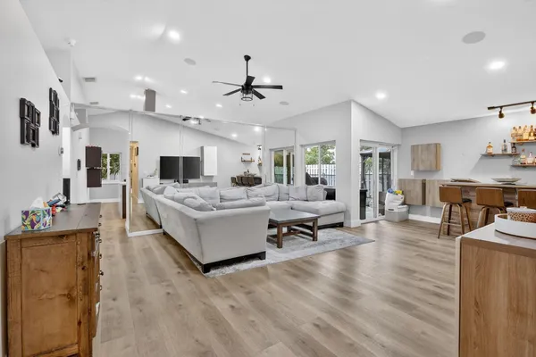 a living room with furniture kitchen view and a wooden floor